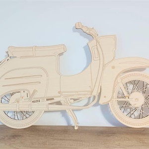 Op de afbeelding: Een lichtbruine houten uitgesneden vintage scooter. Het ontwerp toont gedetailleerde contouren van de carrosserie, wielen en het stuur. De scooter van hout bevat een zadel, spatborden en een standaard.