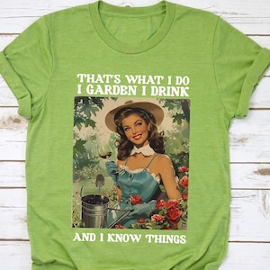 May include: Green t-shirt with a vintage illustration of a woman gardening and holding a glass of wine. The text on the shirt reads "That's what I do I garden I drink and I know things."