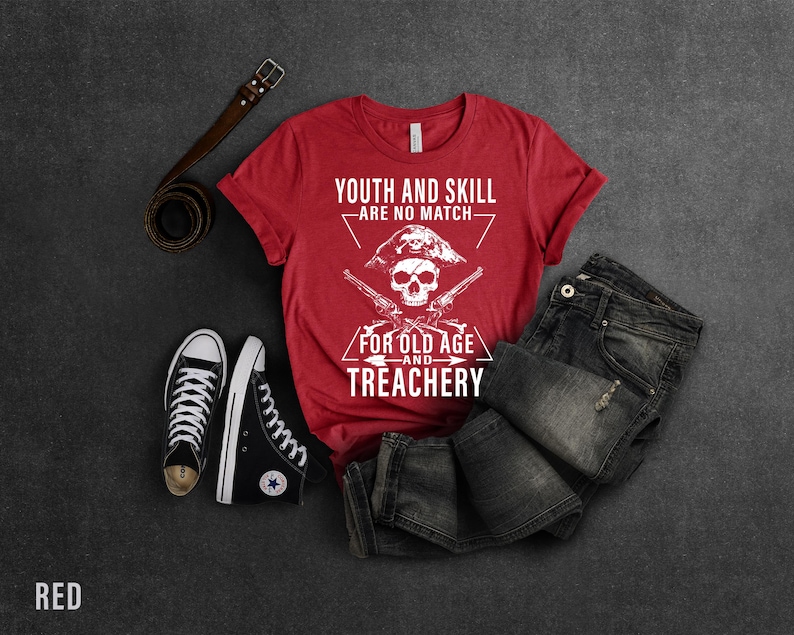 May include: Red t-shirt with a white skull and crossbones graphic. The text on the shirt reads "Youth and skill are no match for old age and treachery".