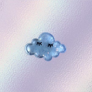 May include: A light blue cloud-shaped resin charm with glitter and black eyes. The cloud has a 3D effect.