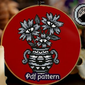 May include: A cross stitch pattern featuring a black and white vase with three stylized flowers with eyes. The vase and flowers are on a red background. The text "Pdf pattern" is at the bottom of the image.