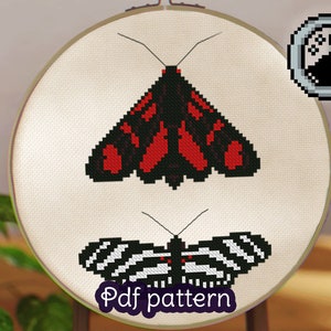 May include: Cross stitch pattern featuring two moths, one with black and red wings and the other with black and white wings. The pattern is displayed on a white fabric stretched over a wooden embroidery hoop. The text "Pdf pattern" is printed below the moths.