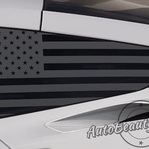 May include: A black and white American flag decal applied to the rear quarter window of a white car. The decal is made of vinyl and is designed to look like a distressed flag. The decal is a popular way to show patriotism and support for the United States.