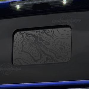 May include: Black truck tailgate with a black and gray patterned window overlay. The overlay has a wood grain design. The text "Auto Beauty Designs" is visible in the image.