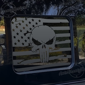 May include: A black and white decal of the Punisher skull superimposed on a distressed American flag. The decal is on a black car window.