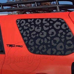 May include: A red car with a black roof rack and a black leopard print decal on the back window. The car has a "TRD PRO" emblem on the side.