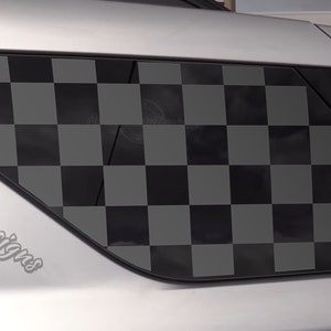 May include: A silver car with a black and gray checkered window tint. The car has a logo on the side that says "Auto Beauty Designs".