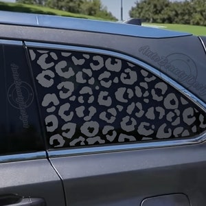 May include: A gray car with a leopard print decal on the back window. The decal is a dark gray on a lighter gray background.