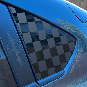 May include: A blue car with a black and white checkered pattern on the rear window. The pattern is a popular racing design. The car has a black trim around the windows.