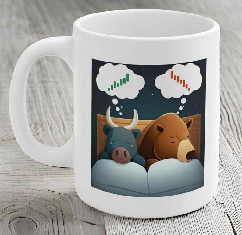 May include: White ceramic coffee mug with a cartoon illustration of a bull and a bear sleeping in a bed. The bull is dreaming of a green upward stock chart and the bear is dreaming of a red downward stock chart.