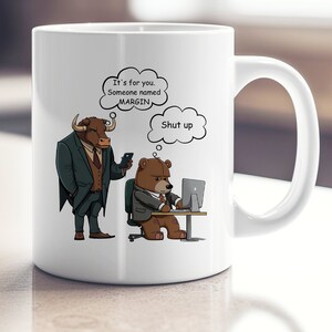 May include: White ceramic mug with a cartoon bull and bear illustration. The bull is wearing a suit and tie and is holding a phone. The bear is wearing a suit and tie and is sitting at a desk with a computer. The text on the mug reads "It's for you. Someone named MARGIN. Shut up."