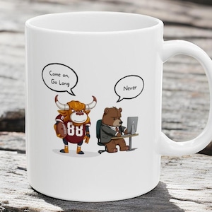 May include: White ceramic coffee mug with a cartoon bull wearing a football jersey and holding a football. The bull is saying "Come on, Go Long". A cartoon bear wearing a suit is sitting at a desk with a computer and saying "Never".