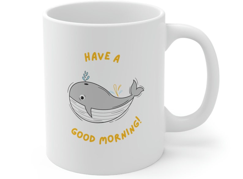 May include: White ceramic coffee mug with a gray whale illustration and the text "Have a good morning!" in yellow.