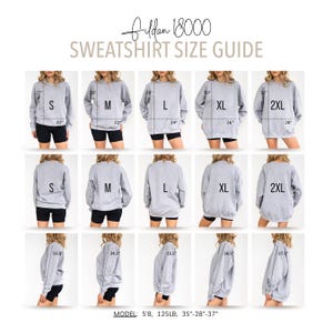 Puede incluir: Una gu&iacute;a de tallas para sudaderas Gildan 18000. La gu&iacute;a muestra m&uacute;ltiples vistas de una sudadera gris en tallas S, M, L, XL y 2XL. Las medidas se proporcionan en cm para cada talla, incluyendo pecho, largo y largo de manga. La modelo mide 173 cm y pesa 57 kg.