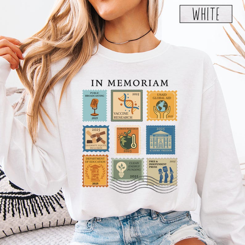 Pode incluir: Camisola branca com um design de selos coloridos. Os selos apresentam ilustra&ccedil;&otilde;es e texto, incluindo "IN MEMORIAM", "PUBLIC BROADCASTING", "VACCINE RESEARCH", "USAID GLOBAL AID", "DIVERSITY EQUITY INCLUSION", "CLIMATE RESEARCH", "ACADEMIC FREEDOM", "DEPARTMENT OF EDUCATION", "CLEAN ENERGY FUNDING" e "FREE & INDEPENDENT PRESS".