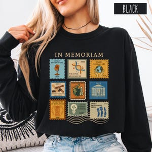 Pode incluir: Camisola preta com a inscri&ccedil;&atilde;o "IN MEMORIAM" e nove desenhos de selos postais. Os selos apresentam ilustra&ccedil;&otilde;es e texto sobre radiodifus&atilde;o p&uacute;blica, investiga&ccedil;&atilde;o de vacinas, ajuda global e outros temas. A palavra "BLACK" est&aacute; impressa num ret&acirc;ngulo branco.