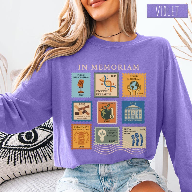 Pode incluir: Uma camisa violeta de manga comprida com as palavras "IN MEMORIAM" acima de nove gr&aacute;ficos em estilo selo postal. Cada gr&aacute;fico apresenta texto e o ano de 2025 ou 2026. A palavra "VIOLET" est&aacute; em um ret&acirc;ngulo no canto superior direito.