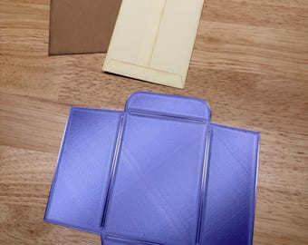 May include: A set of three envelopes including one brown paper envelope, one cream paper envelope, and one unfolded purple plastic envelope template with a flat rectangular base and four rectangular flaps extending from the sides.