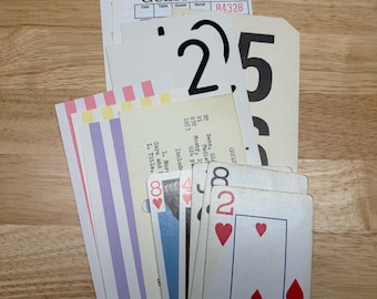 May include: A collection of assorted paper ephemera including a white Guest Check pad, a cream-coloured card with the large black number 25, a vintage library card, and several playing cards featuring the two of hearts and other suit symbols.