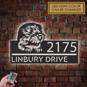 May include: A black metal house number sign with a white LED light. The sign features a beaver silhouette and the address "2175 LINBURY DRIVE". The LED light colour can be changed with a remote control.