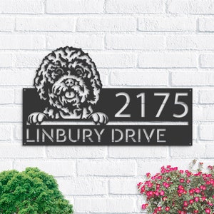 Może przedstawiać: Czarny metalowy znak z numerem domu, na którym widać białego pudla wystającego z góry. Znak zawiera napis "2175 Linbury Drive".
