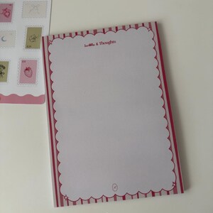 Bloc de notas "Garabatos y Pensamientos" – Bloc de notas rosa suave con bordes festoneados.