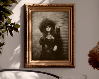 May include: A framed sepia-toned portrait of a woman in a dark dress and large hat, holding a black cat. The ornate gold frame surrounds the image, which is mounted on a neutral-colored wall. The image is from Heather Maree Design Studio.