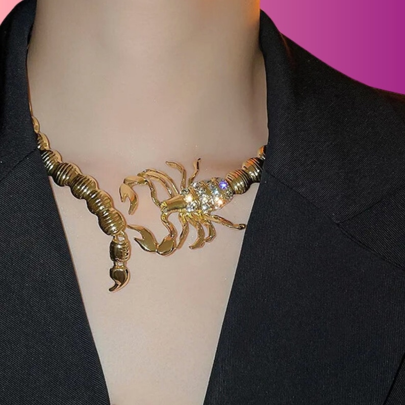 May include: A gold-tone necklace with a large scorpion pendant encrusted with clear rhinestones.