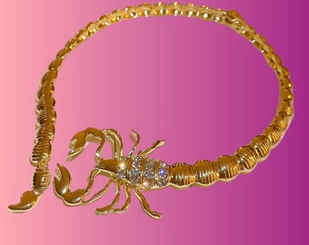 Könnte beinhalten: Eine goldfarbene Skorpion-Halskette mit klaren Strasssteinen. Der Skorpion ist detailliert und hat einen eingerollten Schwanz.