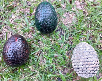 May include: Three dragon egg-shaped ornaments, one green, one black, and one silver.
