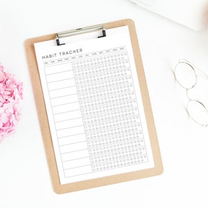 May include: A black and white habit tracker printable on a clipboard with the months of the year listed across the top.