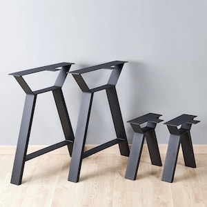 May include: A set of four black metal furniture legs featuring a trapezoidal frame design. The collection includes two tall, large-scale legs and two shorter, smaller-scale legs, all constructed with flat mounting plates at the top for attachment.
