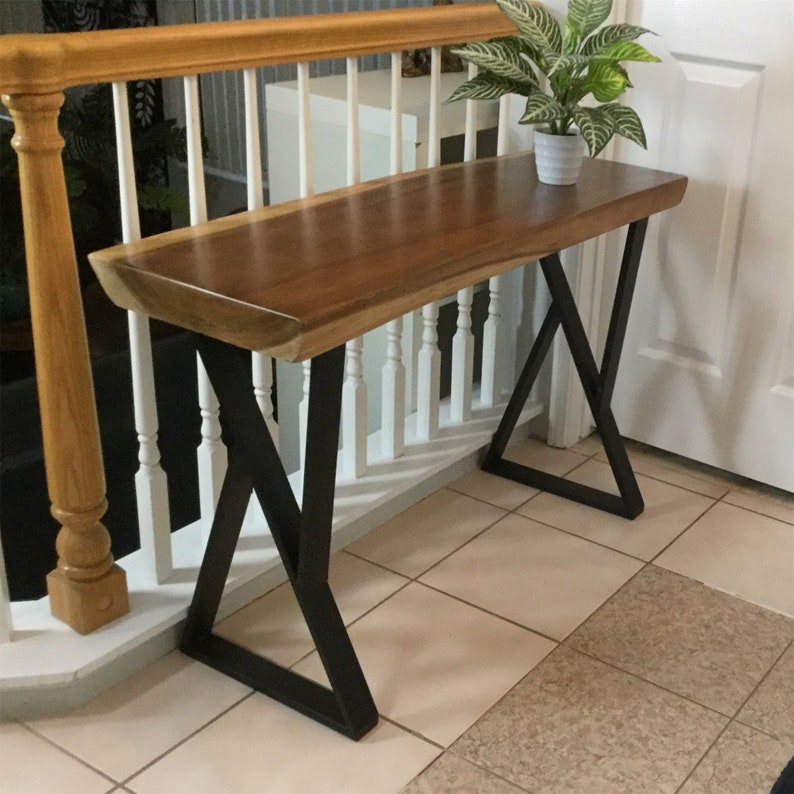 May include: A wooden console table with a live edge top and black metal legs. The table is 30 inches tall and 48 inches wide.