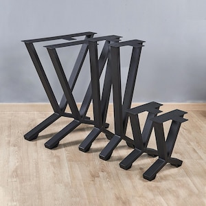 May include: Four black metal table legs in different sizes. The legs are shaped like an upside-down V with a crossbar at the top.