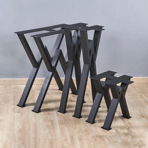 May include: Three black metal table legs in different sizes. The legs are in an X shape and are made of thick metal.
