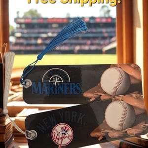 May include: Two baseball-themed bookmarks. One features the Seattle Mariners logo and the other the New York Yankees logo. Each bookmark has a baseball and glove design and a blue tassel.