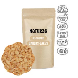 Può includere: Una confezione marrone di fiocchi di aglio disidratati Naturzo. La confezione presenta la scritta "Naturzo", "Dehydrated Garlic Flakes" e icone che indicano che il prodotto è naturale, vegano e privo di lattosio, glutine e OGM. Un mucchio di fiocchi di aglio davanti.