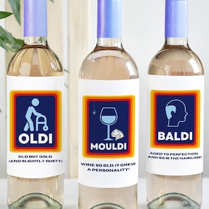 Puede incluir: Tres botellas de vino con etiquetas humorísticas. Las etiquetas presentan ilustraciones y texto que hacen referencia al envejecimiento. La primera etiqueta dice "Oldi" con una ilustración de una persona usando un andador y el texto "Old but gold (and slightly rusty)". La segunda etiqueta dice "Mouldi" con una ilustración de una copa de vino y el texto "Wine so old it grew a personality!". La tercera etiqueta dice "Baldi" con una ilustración de una cabeza calva y el texto "Aged to perfection and so is the hairline."
