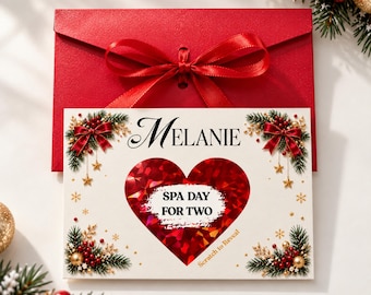 Könnte beinhalten: Eine rechteckige weiße Karte mit dem Namen Melanie, bedruckt mit einem großen roten Herz mit einer Rubbelfläche mit der Aufschrift SPA DAY FOR TWO, umgeben von Tannenzweigen, roten Schleifen, goldenen Sternen und einem roten Umschlag mit Schleife.