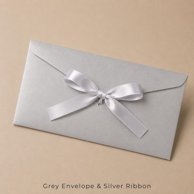 Op de afbeelding: Een rechthoekige zilverkleurige envelop met een metallic afwerking, voorzien van een centraal geplaatst zilveren satijnen lint gestrikt tot een decoratieve strik. De envelop heeft een puntige klep en toont de tekst Grey Envelope & Silver Ribbon.