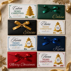 May include: A collection of rectangular envelopes in white, dark green, black, navy blue, and red. The white envelopes feature gold foil Christmas trees and personalised text like Calvin, Elaine, Kevin, and Fionn. Coloured envelopes have satin bows.
