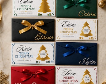 Könnte beinhalten: Eine Sammlung rechteckiger Umschläge in Weiß, Dunkelgrün, Schwarz, Marineblau und Rot. Die weißen Umschläge zeigen goldene Weihnachtsbäume und personalisierte Texte wie Calvin, Elaine, Kevin und Fionn. Die farbigen Umschläge haben Satin-Schleifen.