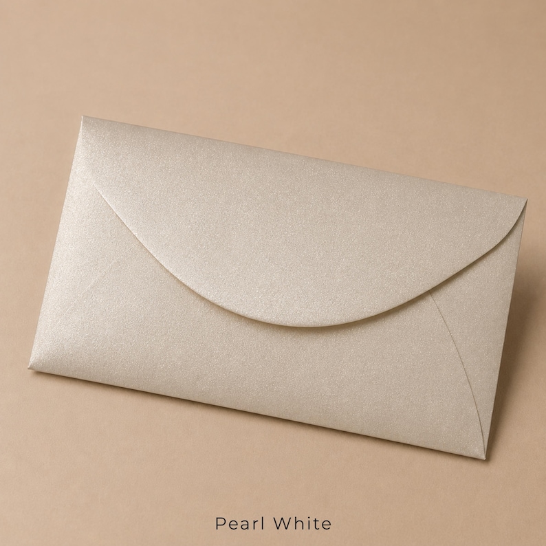Op de afbeelding: Een rechthoekige envelop met een gebogen klep in een glinsterende parelwitte afwerking. Het papier heeft een subtiele metallic textuur die het licht over het oppervlak weerkaatst. De tekst Pearl White staat onderaan in een zwart lettertype.