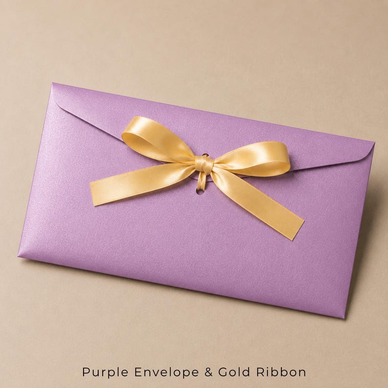 Op de afbeelding: Een rechthoekige lavendelkleurige envelop met een glinsterende afwerking, voorzien van een centraal geplaatst gouden satijnen lint gestrikt tot een strik. De envelopflap wordt vastgehouden door het lint dat door een opening gaat.