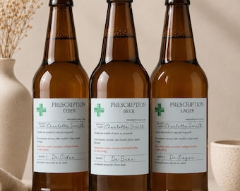 Può includere: Tre bottiglie di vetro marrone con tappi dorati, ognuna con un'etichetta bianca progettata come una ricetta medica. Le etichette presentano una croce verde, il testo Prescription Cider, Beer o Lager e il nome Charlotte Smith.