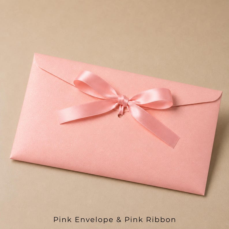 Op de afbeelding: Een rechthoekige lichtroze envelop met een gladde, matte textuur. De envelop is afgesloten met een bijpassend lichtroze satijnen lint dat in het midden van de klep tot een decoratieve strik is gestrikt voor een strak en uniform uiterlijk.