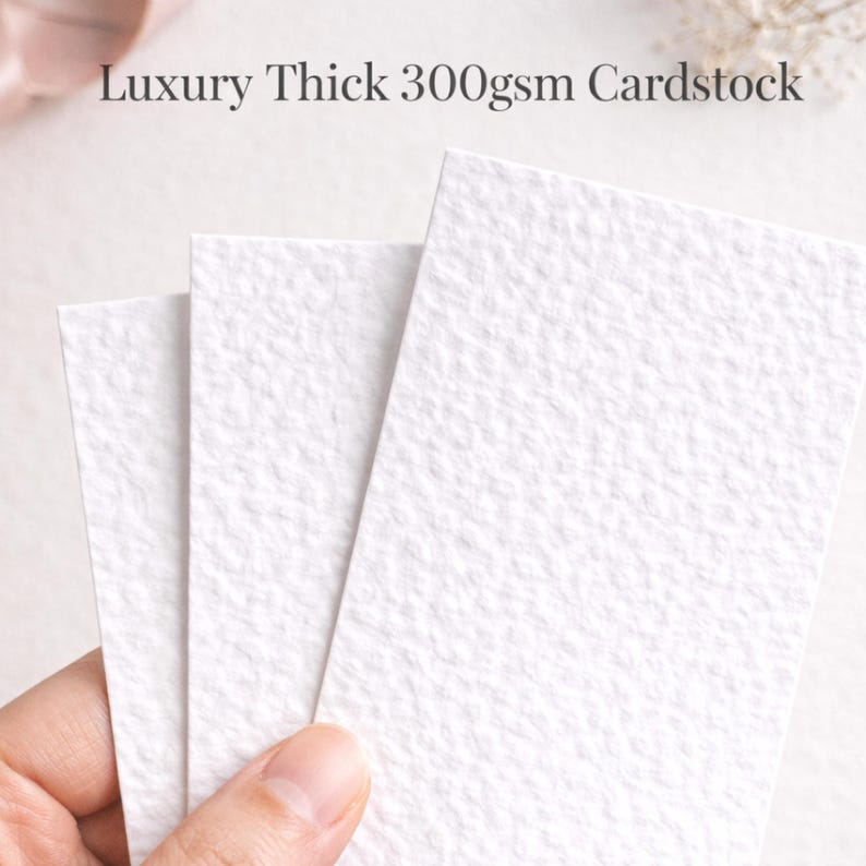 May include: Three white textured cardstock sheets are shown, with the text "Luxury Thick 300gsm Cardstock" at the top. The paper has a subtle, organic texture. The sheets are held by a hand.