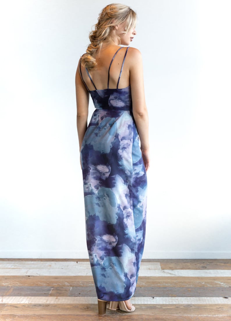 May include: A long, flowing maxi dress with a blue and purple watercolor print. The dress has a V-neckline and thin straps.