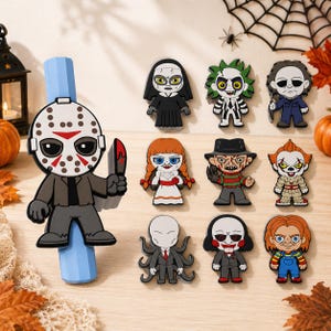 Peut inclure: Un ensemble de dix breloques en caoutchouc coloré représentant divers personnages de films d'horreur, dont une breloque Jason Voorhees fixée sur un embout de crayon bleu clair, avec neuf autres designs de personnages d'horreur distincts.