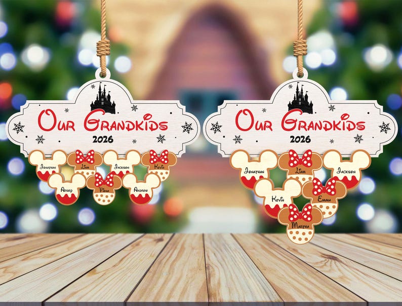 May include: Two wooden Christmas ornaments with the text "Our Grandkids 2026". Each ornament features Mickey Mouse head-shaped cookies with names and red bows. A black castle silhouette is at the top.